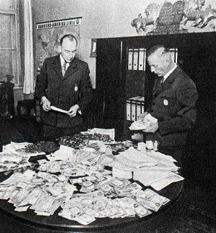 black and white photo of Biebow and another Nazi official looking at loot that was raided from the ghetto 