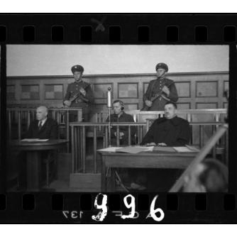 black and white photo of Biebow sitting in a trial box with arm guards on both sides of him 